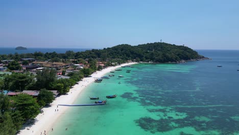 Tourists-are-enjoying-a-sunny-day-on-a-tropical-island-beach-with-traditional-thai-longtail-boats-moored-in-the-turquoise-water