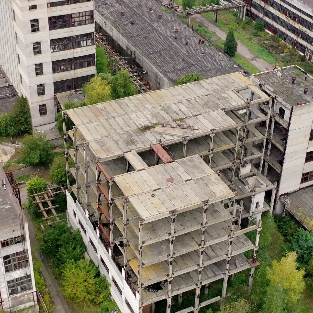 Unfinished old building without windows on a factory. Abandoned territory of industrial plant with empty buildings and warehouses. Aerial view