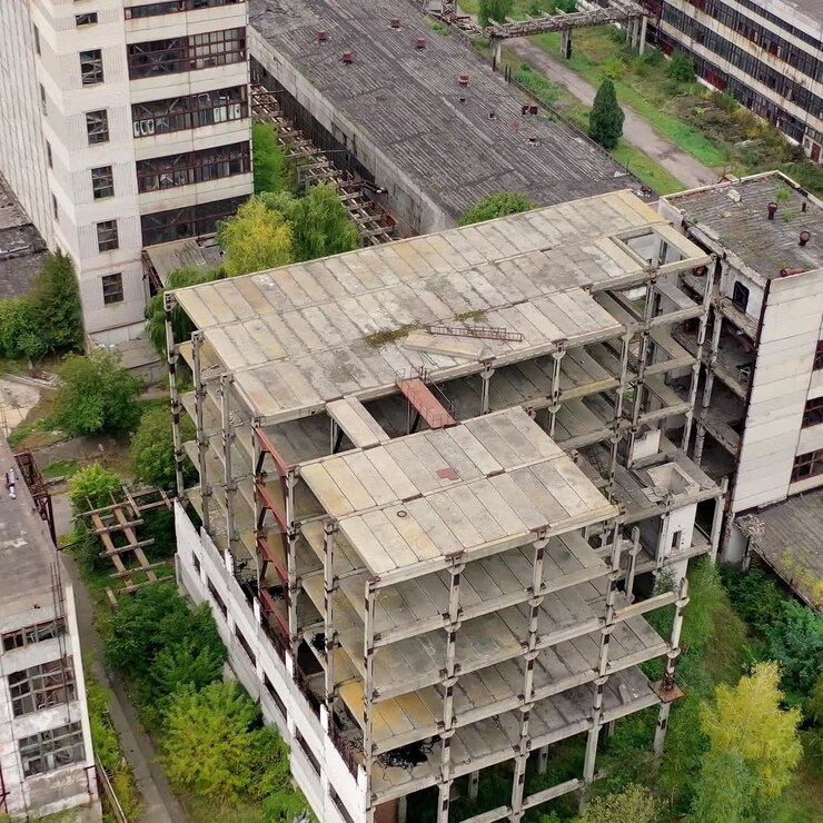 Edificio antiguo sin terminar y sin ventanas en una fábrica. Territorio abandonado de una planta industrial con edificios y almacenes vacíos. Vista aérea