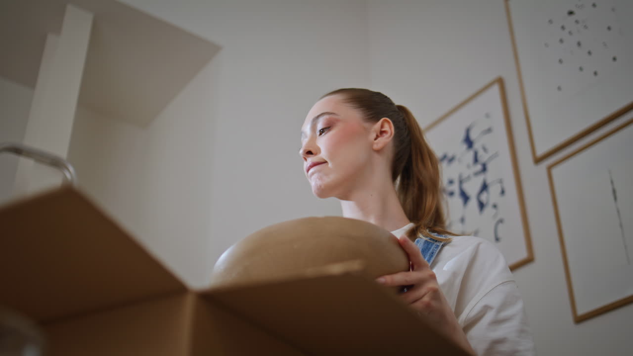 New owner unpacking cardboard box in own home feeling thoughtful closeup