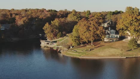 Low-altitude-aerial-view-of-lake-homes-with-boat-dock-and-fall-colors