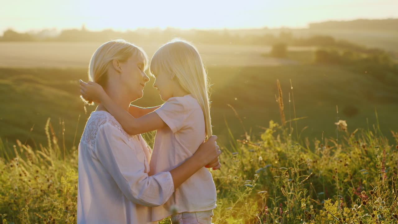 야외에서 그녀의 금발 머리를 쓰다듬어 그녀의 아이를 진정 젊은 어머니