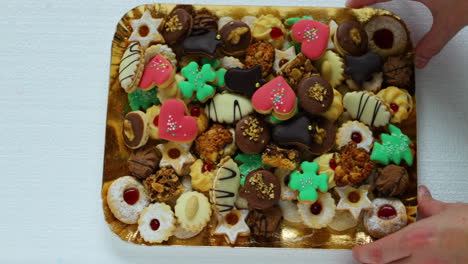 a hand that moves to the side of a christmas candy, which is laid on a gold plate decorated and stacked wearing different colors of species and sizes in slow motion capture at 120fps