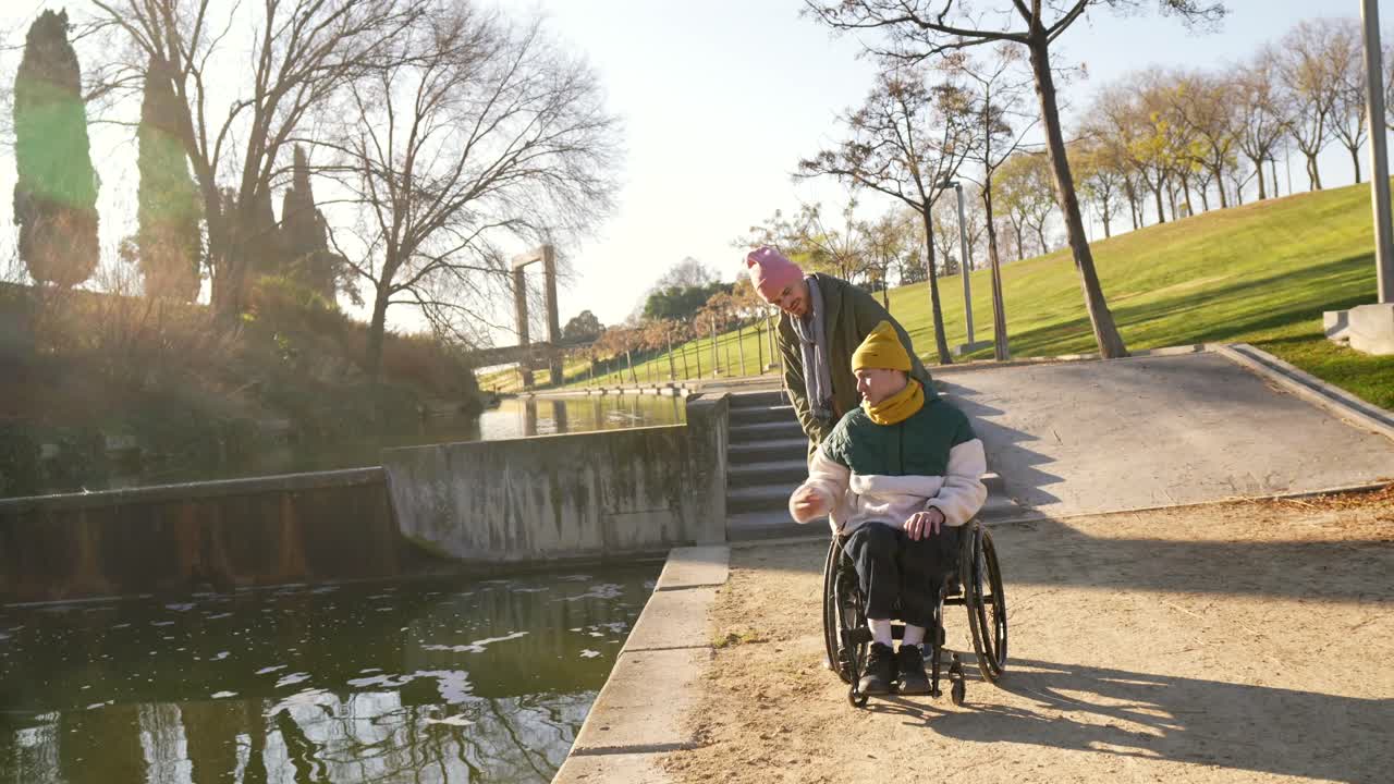 A disabled man in a wheelchair enjoying a walk in the park with a friend