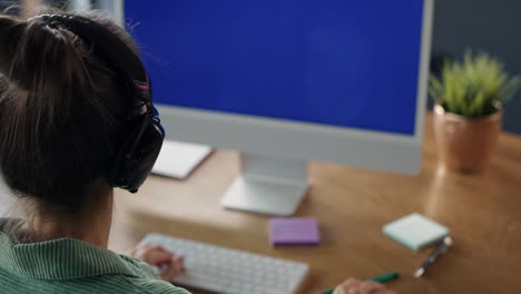 Rear view of woman working on computer with blue screen