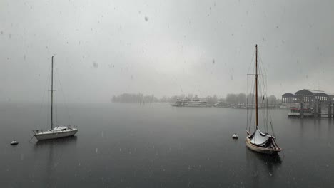 Nieve-Cayendo-Sobre-El-Lago-Maggiore-Y-Velero-Anclado-Y-Ferry,-Italia