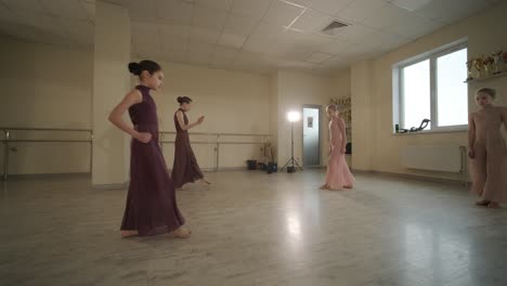 a group of young ballet students in black dancewear practicing positions in a spacious ballet studio with wooden flooring and wall-mounted barres. focused expressions and synchronized movements.