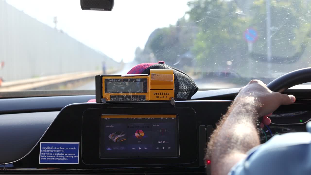 A driver's view from inside a car navigating a sunny road in Phuket, Thailand, capturing the journey and surroundings