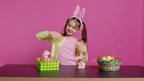 smiling confident toddler placing bunny ears on her head and waving