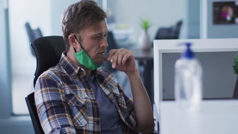 Portrait-of-smiling-caucasian-man-with-face-mask-in-office