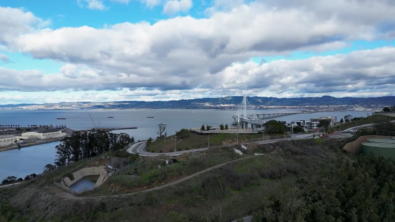 A smooth drone push-in reveal shot of The Bay Bridge from Yerba Buena Island, CA, showcasing the bridge and scenic bay. Ideal for urban, transportation, and travel footage.