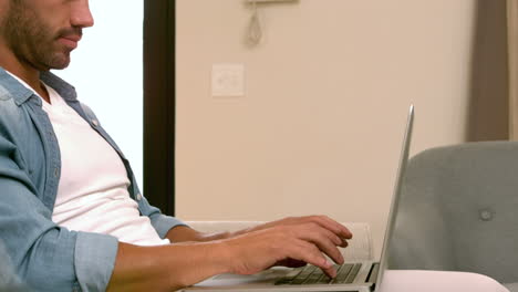 Smiling-man-using-laptop-on-the-sofa