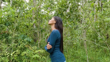 young woman with long black hair breath in the forest