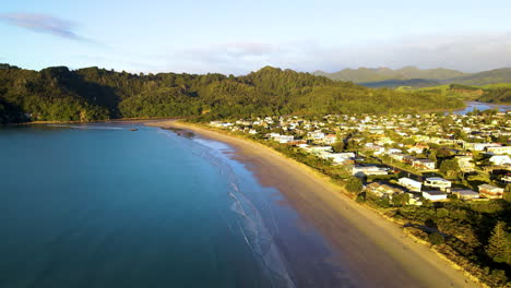 Toma-Aérea-De-Playa-De-Arena-Y-Casas-En-La-Península-De-Coromandel,-Nueva-Zelanda