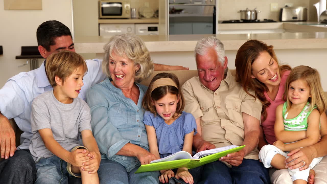 Extended family looking at photo album together on couch