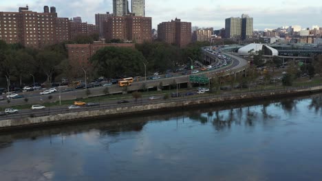 Inclinación-Aérea-Hacia-Abajo-Con-Proyecto-De-Vivienda-Y-Tráfico-En-El-Río-Harlem-En-La-Ciudad-De-Nueva-York