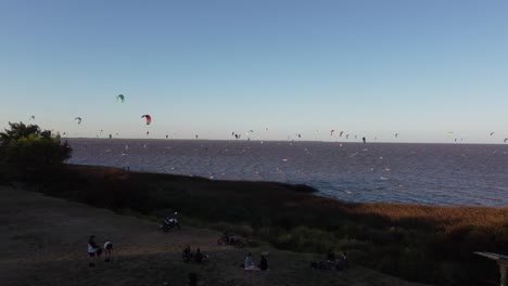 many kitesurfers along rio de la plata river at sunset, vicente lopez area, buenos aires in argentina