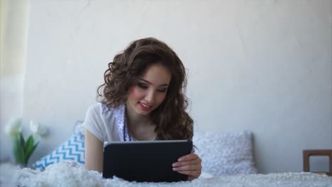 young woman relaxing on a bed with tablet