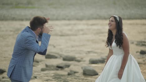 Wedding-couple-standing-near-mountain-river.-Groom-and-bride-making-faces