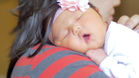 a newborn baby sleeping on her mother's shoulder