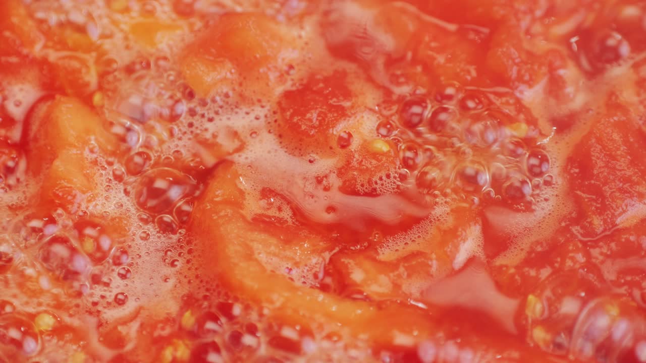 Cooking fresh peeled canned tomato Juice sauce in pan, peeled tomatoes boiling in their own juice, making tomatoes pasta sauce .Top view close up, Italian traditional cuisine food.