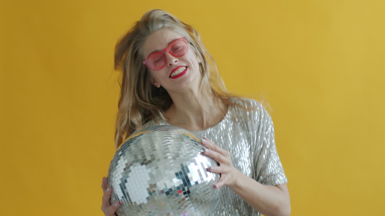 movimiento lento de chica feliz bailando con bola de discoteca disfrutando de la fiesta mientras caen los confeti