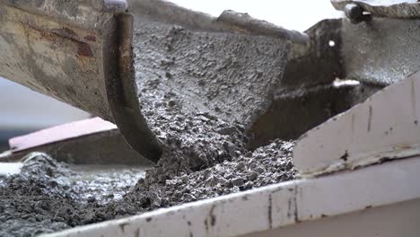 una hormigonera portátil en un lugar de construcción, con cemento cayendo lentamente de un transportador a un contenedor