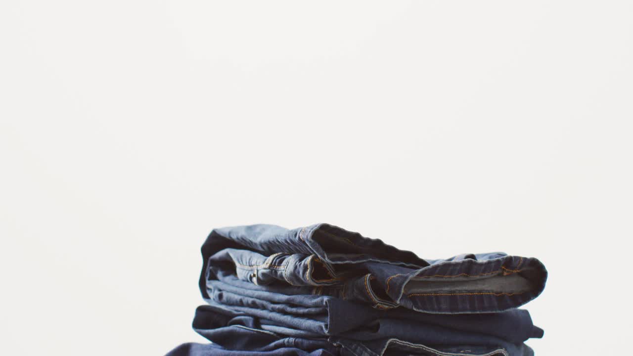 Close up of folded jeans with different shades on white background with copy space