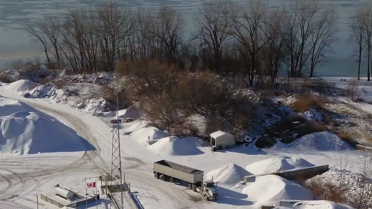 Aerial view of the snowy construction site on the lake, with a truck approaching