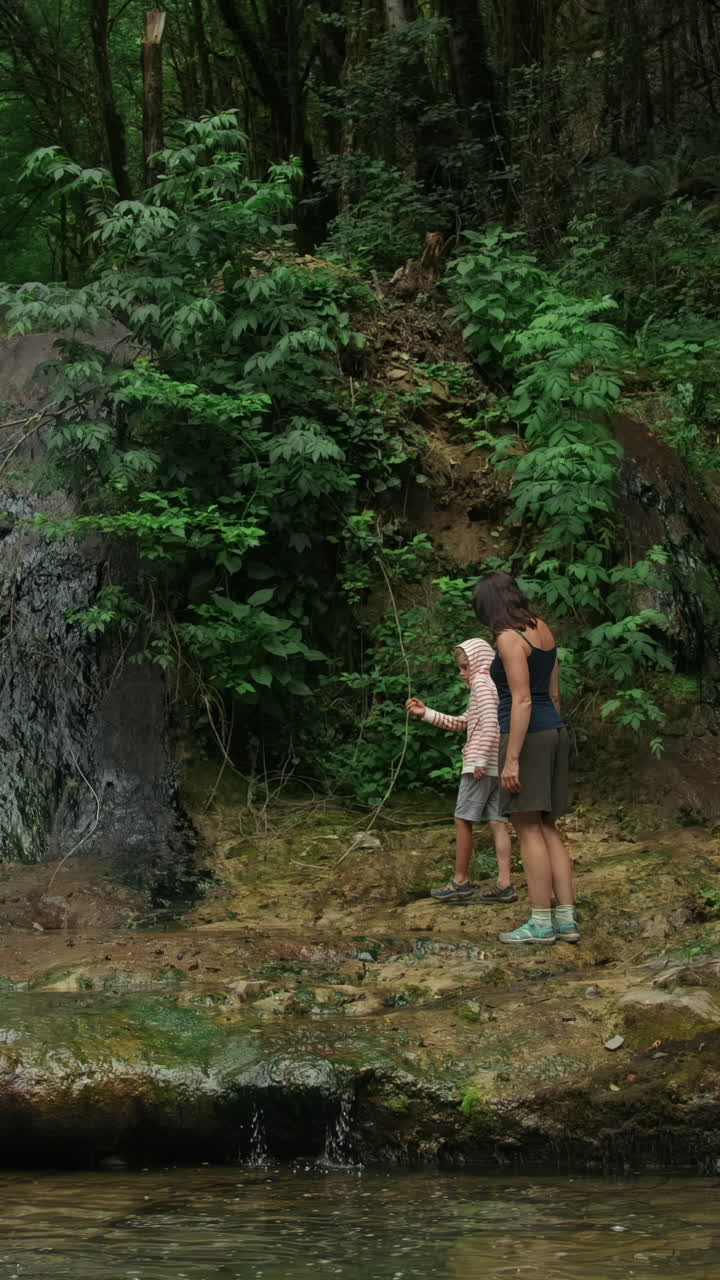 madre e hijo caminando en un bosque junto a un río