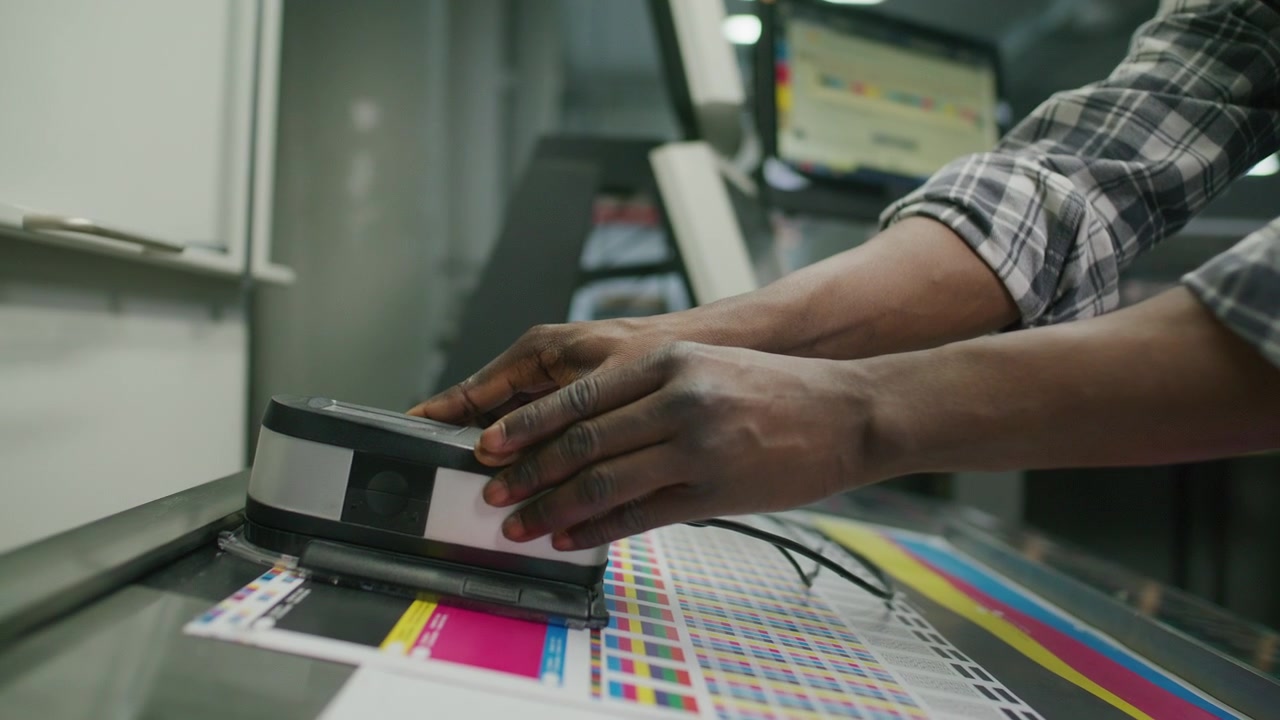 Printing Press Operator Scanning Color Chart with Spectrophotometer
