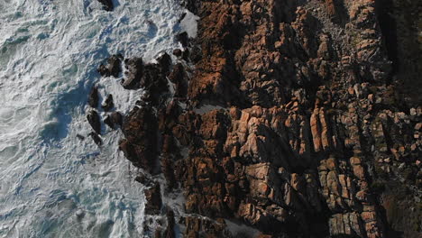 hd pro res 422 nature aerial drone rising motion overlooking rocks, boulders, sea, ocean with white wash waves crashing on rocky beach