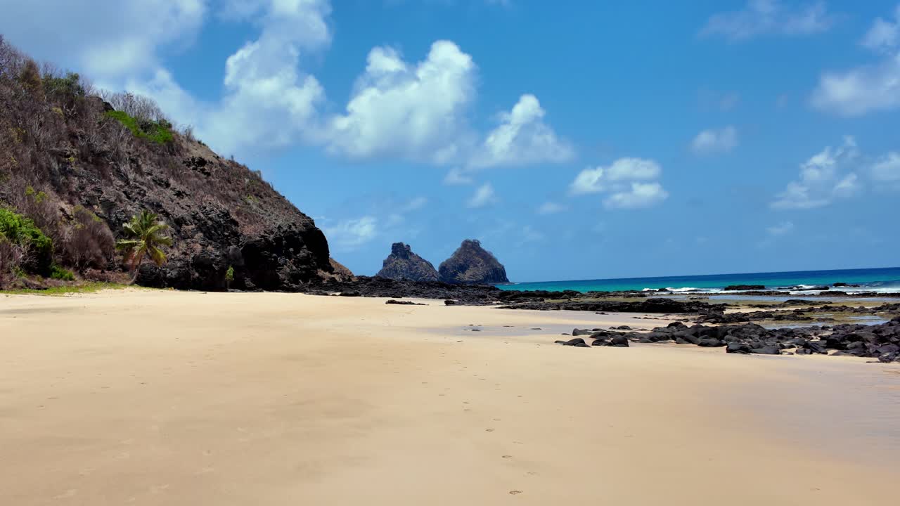 A perfect tropical scene with soft sand, dark rocks and calm turquoise water