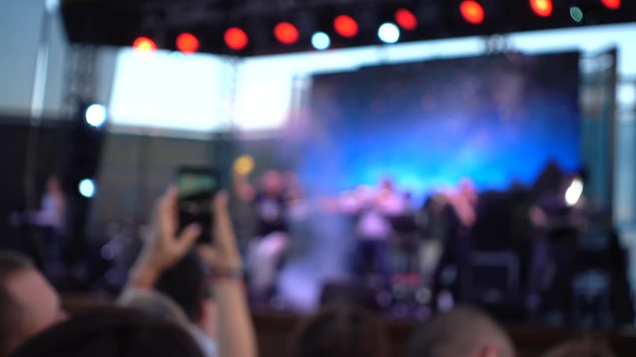 Concerto sul palco. Folla di persone e musicisti sulla scena. Fuori fuoco