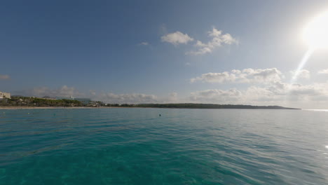 Low-aerial-over-clear-ocean-water-into-sun