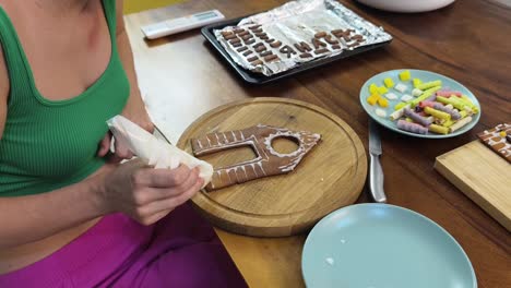 mujer decorando una casa de pan de jengibre