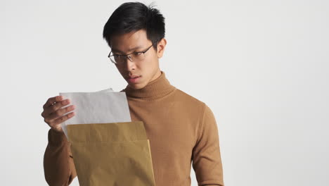 아시아인 남자가 봉투를 열고 내용을 읽고 있습니다.