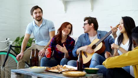 jóvenes amigos felices tienen una fiesta en un apartamento compartido y cantan juntos mientras su amigo toca la guitarra en casa