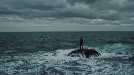 man on a rocky outcrop during a stormy sea