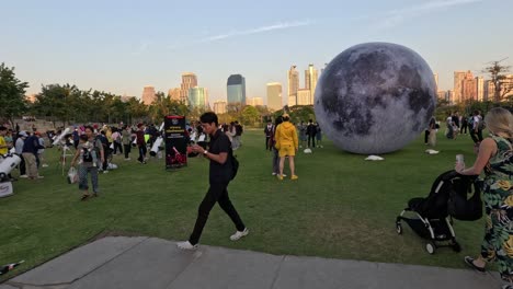 crowd interacting with large moon installation outdoors