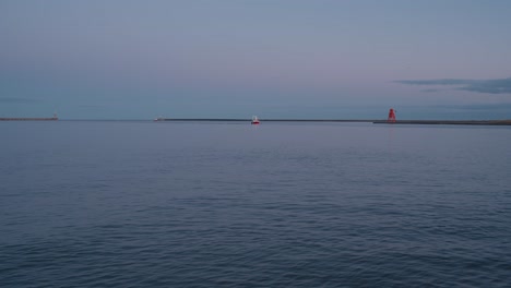 fixed establishing clip of a local commercial red fishing boat returning to harbour from the north sea, late afternoon, followed closely by a pack of seabirds