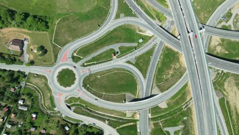 aerial drone zoom-in footage captures intricate highway junction with cars navigating complex roundabouts and intersecting roads