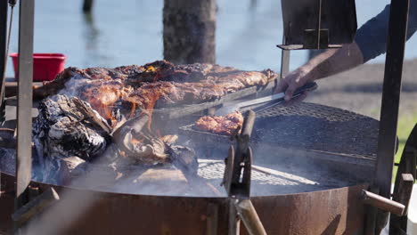 grilled asado argentino meat with smoke and flames rising at barbecue rack.