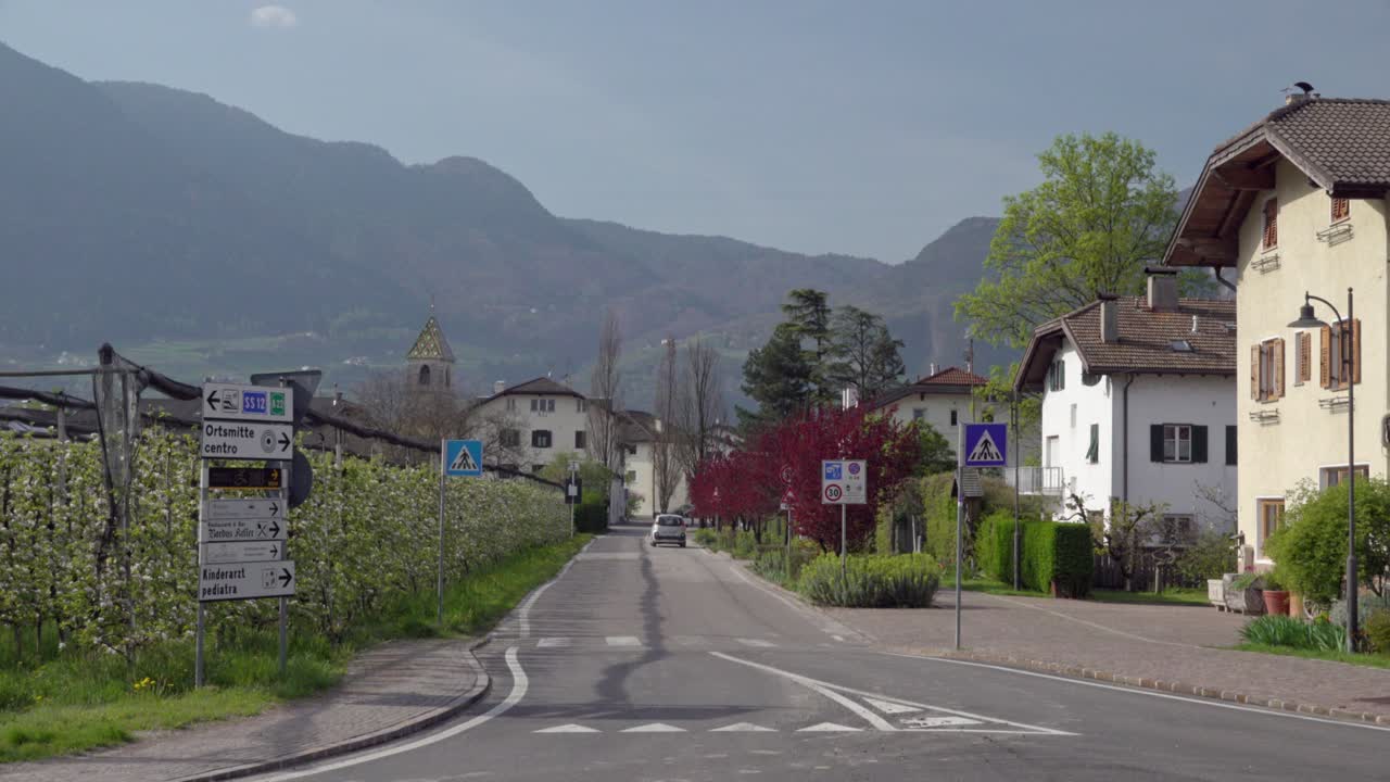 A car driving along a street leading out of town in Kurtinig - Cortina, South Tyrol, Italy