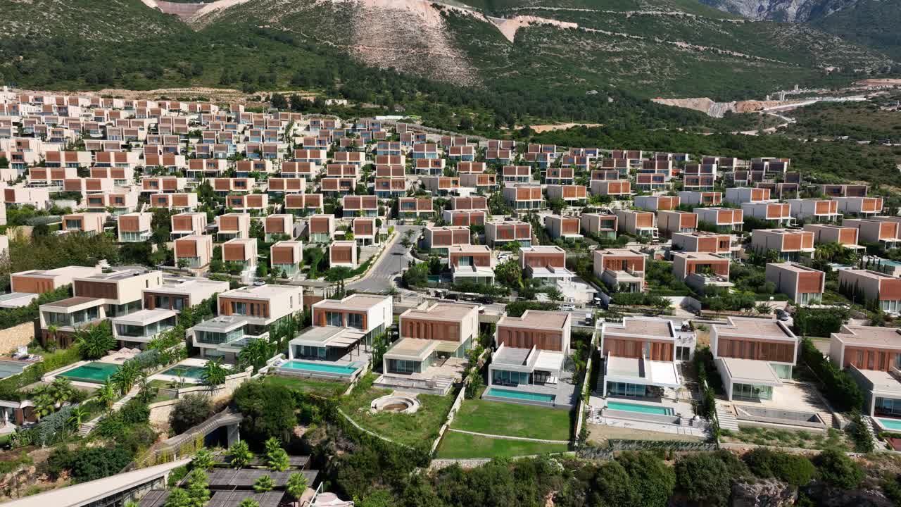 Aerial pan of buildings with pools by green hills at Palase, Albania
