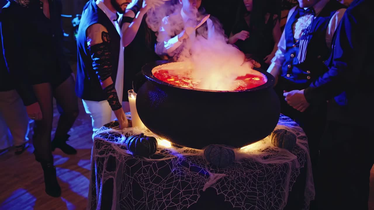 Aerial view of a Halloween party scene with people in costumes around a steaming cauldron