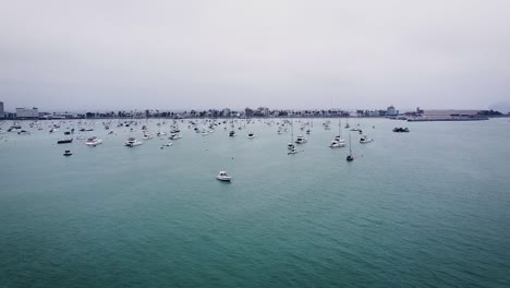 Cinematic-Shot-Of-Boats-Anchored-In-Fabulous-Blue-Seascape,-Bird-Flying-Peacefully,-Peru