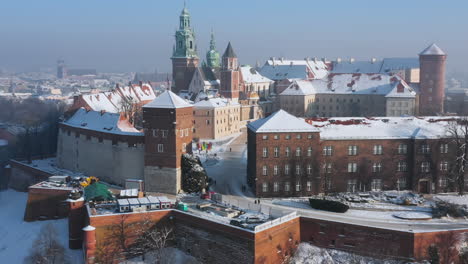 snow-covered wawel castle at magic morning with soft sun light during winter, krakow, poland