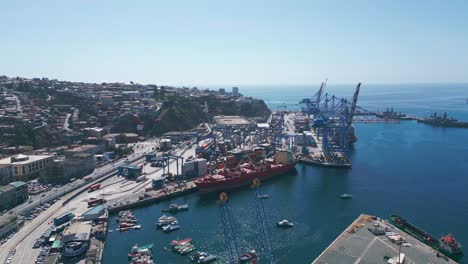 aerial view of busy commercial port with cranes, containers and cargo ships on a sunny day in valparaiso, chile