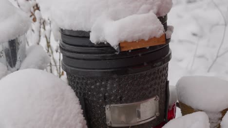 snowing on first day of spring as hibachi barbecue cooking grill covered in snow and baseball softball underneath camera panning up from low angle - in cinema 4k half speed at 30fps